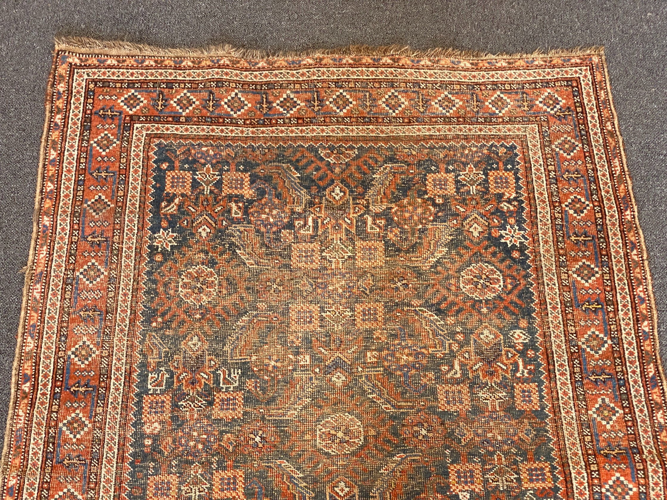 A Shiraz blue ground rug with dense floral field (worn), 144 x 102 cms